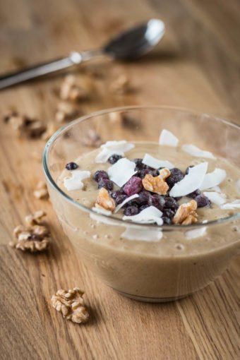 Eine Schale Bananenmus mit Heidelbeeren, Kokosflocken und Walnüssen