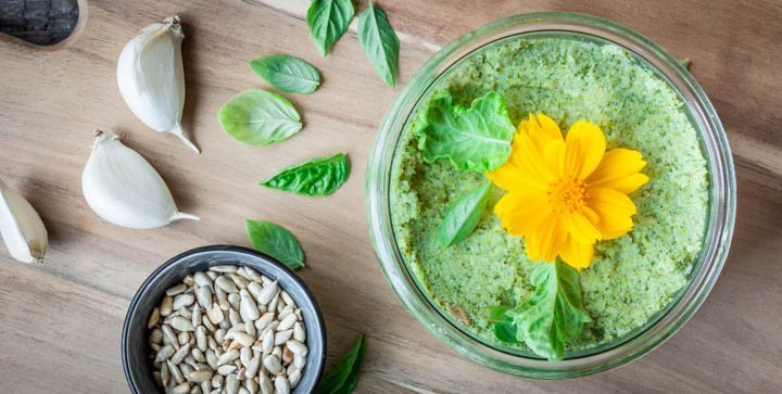 Eine Schale mit grünem Brokkoli-Pesto steht auf einem Holzbrettchen