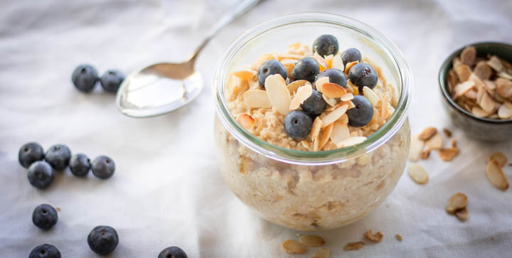 Eine Schale Hafer-Porridge mit Mangostücken, Heidelbeeren und gerösteten Mandelblättern