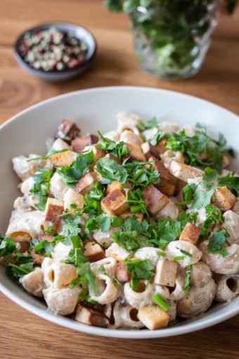 Ein Teller vegane Cashew-Carbonara mit Räuchertofu und Petersilie