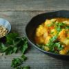 Ein Teller mit Blumenkohl-Linsen-Curry und ein Schälchen mit Koriandersamen