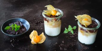 Zwei Gläser mit Kokosmilchreis, Birnenkompott und Schokoladenkruste