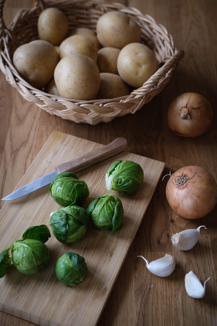 Einige Zutaten für eine Kartoffelsuppe: Kartoffeln, Zwiebeln, Knoblauch und Rosenkohl