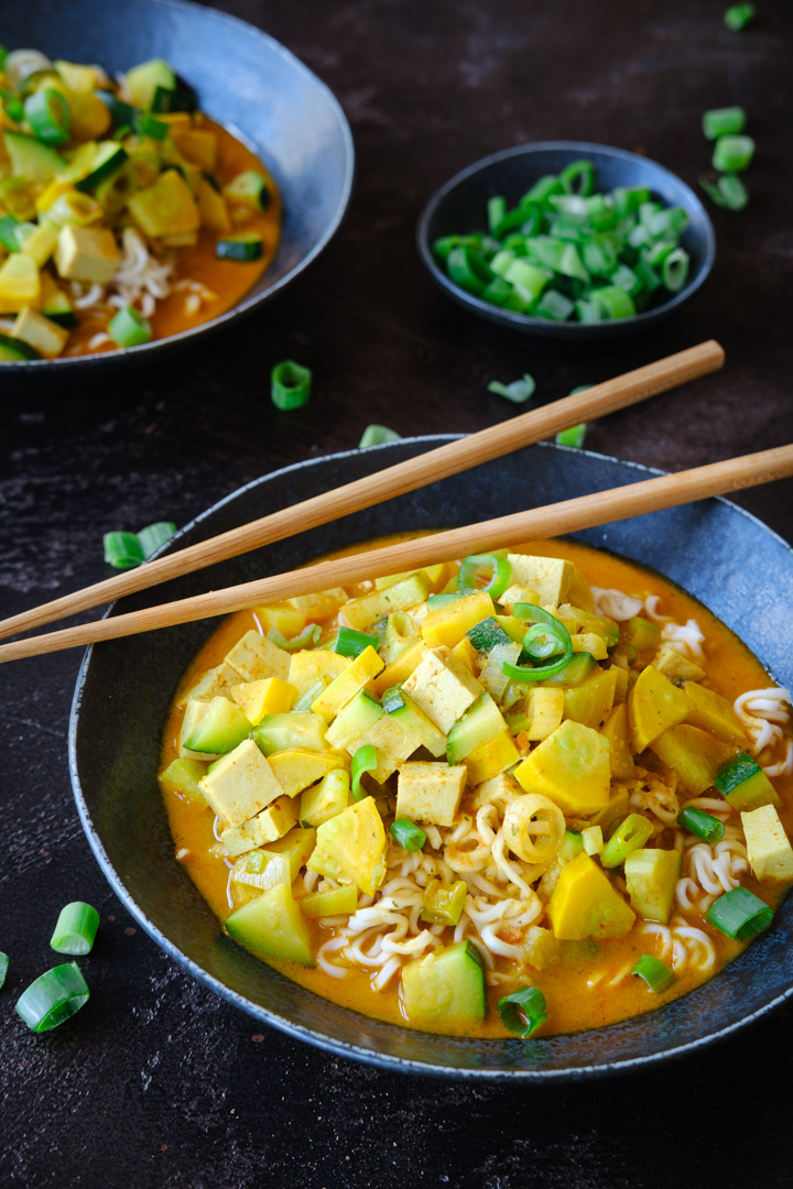 Ein Teller vegane Kokos-Curry-Suppe mit Tofu, Zucchini und Frühlingszwiebeln