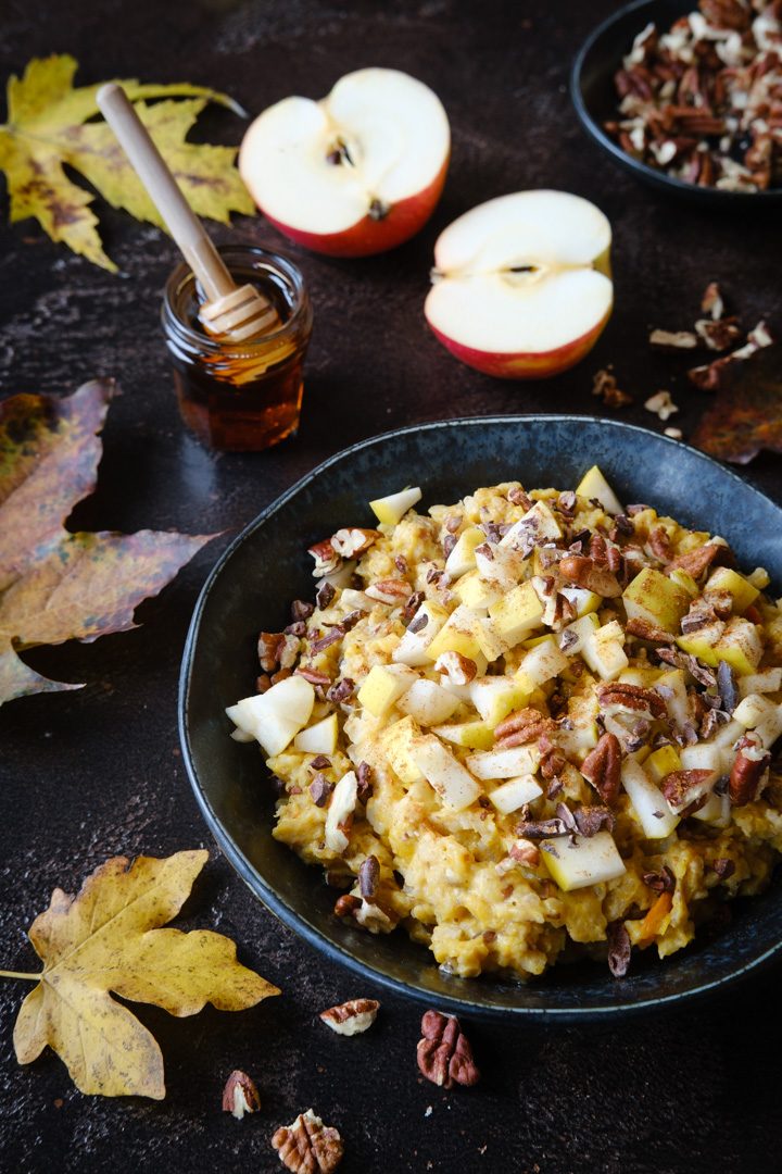 Ein Schälchen veganes Kürbisporridge mit Äpfeln und Pekannüssen