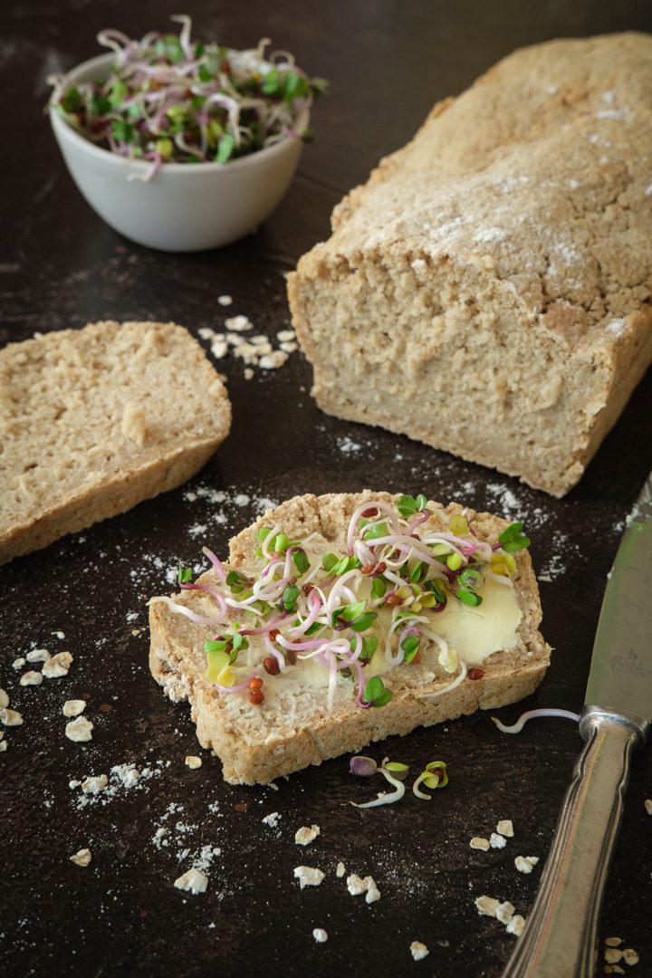 Eine Scheibe selbstgebackenes veganes Haferbrot mit pflanzlicher Butter und Sprossen