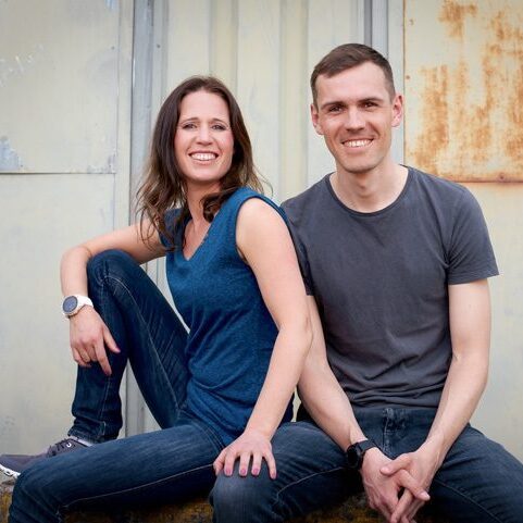 Katrin und Daniel sitzen vor einer grauen Wand