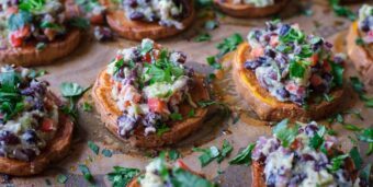 Süßkartoffelscheiben mit Guacamole und Koriandertopping liegen auf einem Backblech