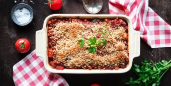 Veganer Auberginenauflauf mit Kichererbsen, Tomatensoße und Haselnuss-Topping in einer Auflaufform